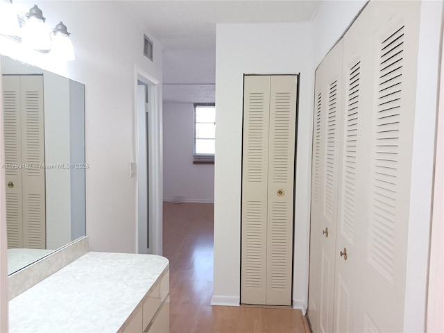 interior space featuring a closet, wood finished floors, visible vents, and baseboards