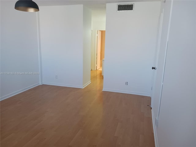 empty room featuring light wood-type flooring, visible vents, and baseboards