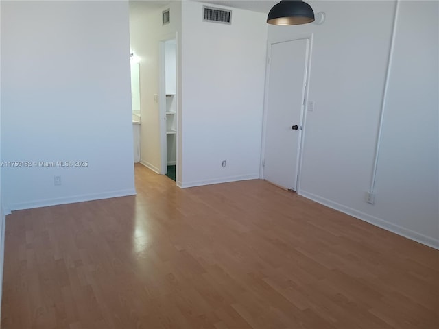 spare room with light wood finished floors, baseboards, and visible vents