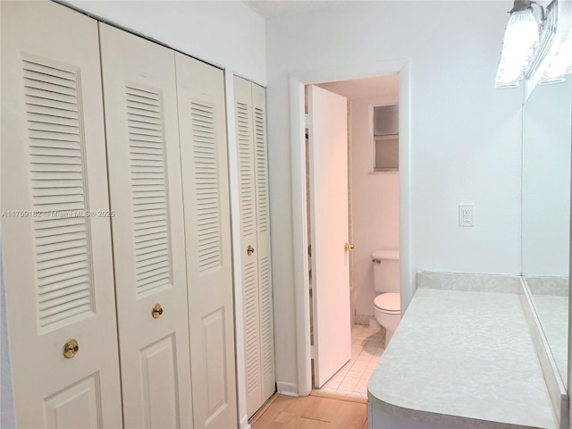 bathroom featuring a closet, wood finished floors, and toilet