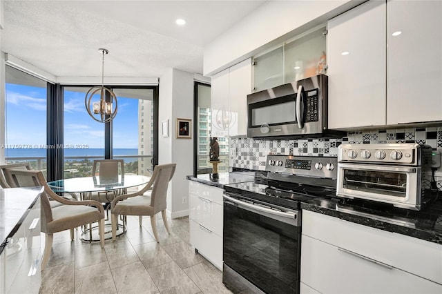 kitchen with a toaster, white cabinets, appliances with stainless steel finishes, a notable chandelier, and backsplash