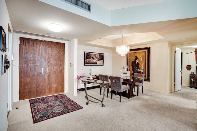 carpeted foyer entrance featuring a raised ceiling, a notable chandelier, baseboards, and visible vents