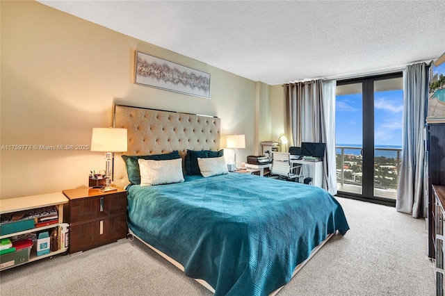 carpeted bedroom featuring floor to ceiling windows, access to outside, and a textured ceiling