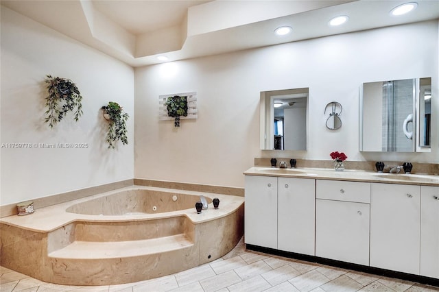 full bath with a sink, a tub with jets, recessed lighting, and double vanity