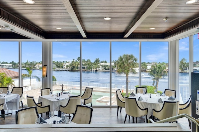 sunroom / solarium featuring beam ceiling and a water view