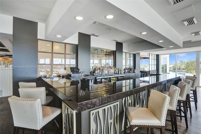 bar featuring visible vents, beverage cooler, wood finished floors, recessed lighting, and a bar