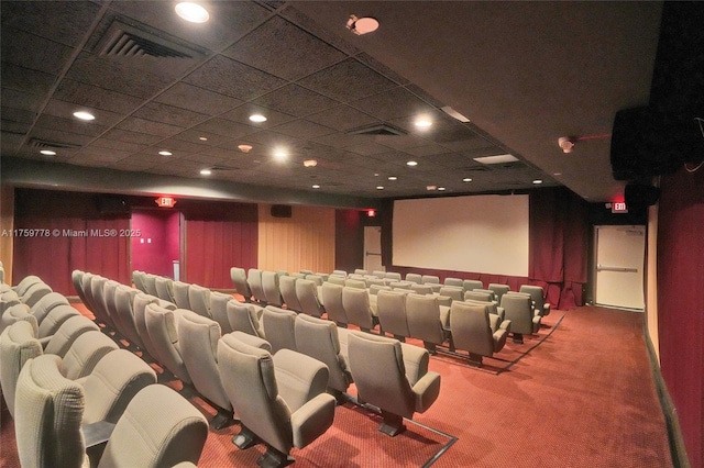 carpeted cinema room with visible vents and a drop ceiling