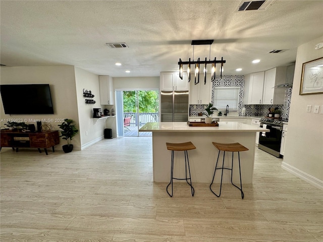 5127 Glasgow Ave, Orlando, FL 32819 - kitchen with a breakfast bar, electric range oven, white cabinetry, visible vents, and a kitchen island