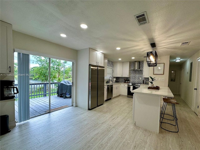 5127 Glasgow Ave, Orlando, FL 32819 - kitchen featuring stainless steel appliances, backsplash, visible vents, light wood-type flooring, and wall chimney exhaust hood