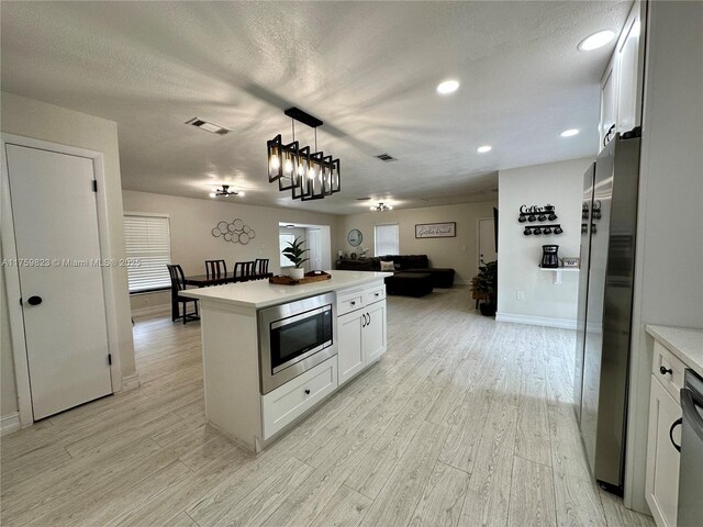 5127 Glasgow Ave, Orlando, FL 32819 - kitchen featuring open floor plan, light countertops, light wood-style flooring, appliances with stainless steel finishes, and visible vents