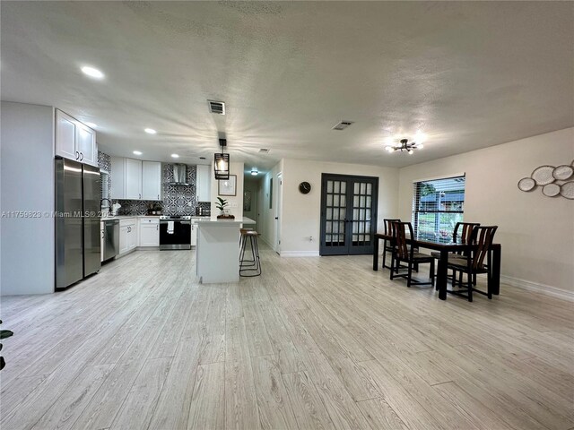 5127 Glasgow Ave, Orlando, FL 32819 - kitchen with stainless steel appliances, a breakfast bar, visible vents, wall chimney exhaust hood, and tasteful backsplash