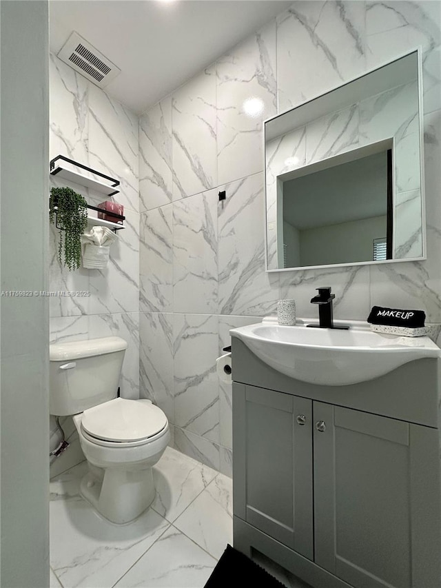 5127 Glasgow Ave, Orlando, FL 32819 - half bath with tile walls, visible vents, marble finish floor, and toilet