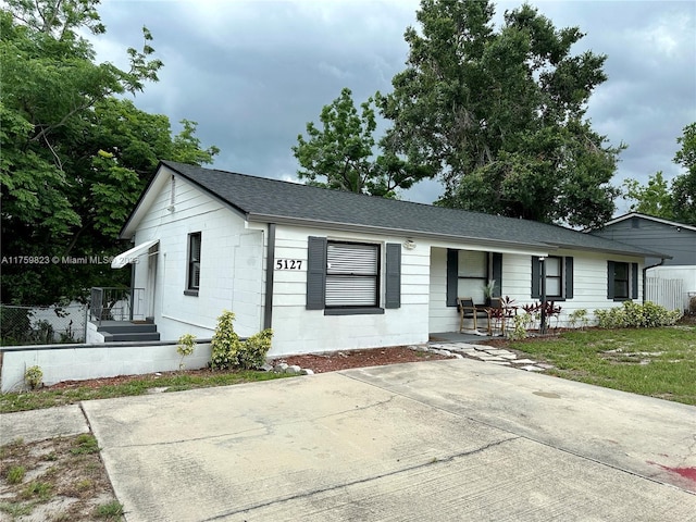 5127 Glasgow Ave, Orlando, FL 32819 - single story home featuring concrete block siding, roof with shingles, a porch, and a front lawn