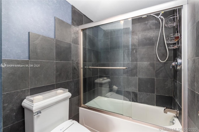 full bathroom featuring tile walls, toilet, and shower / bath combination with glass door