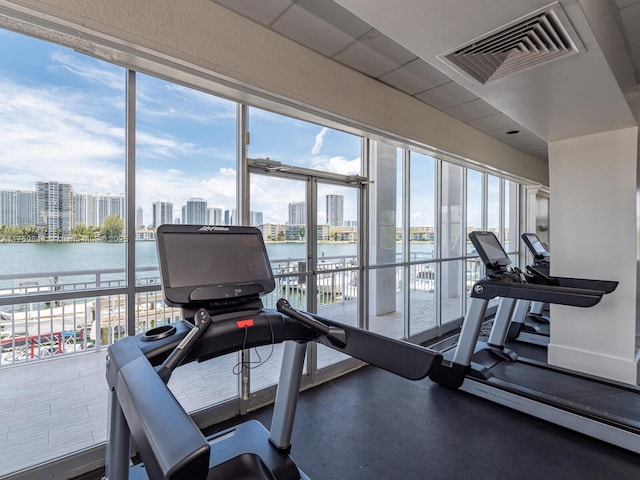 exercise room featuring visible vents, a water view, and a city view