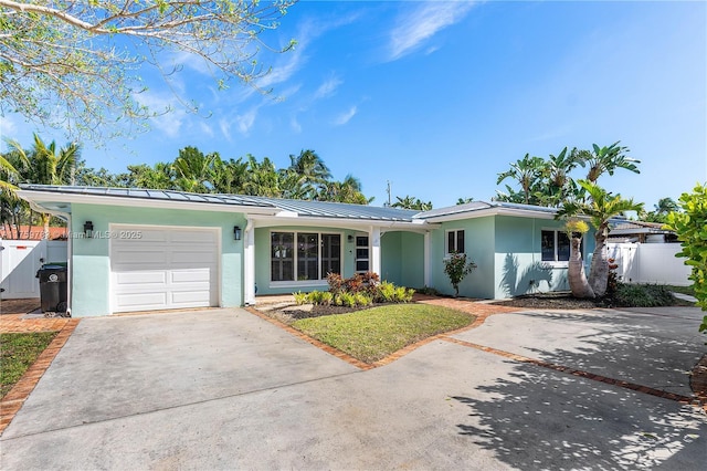 single story home featuring fence, a standing seam roof, stucco siding, concrete driveway, and a garage