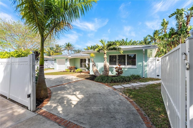 view of front of home featuring a gate, fence, stucco siding, concrete driveway, and metal roof