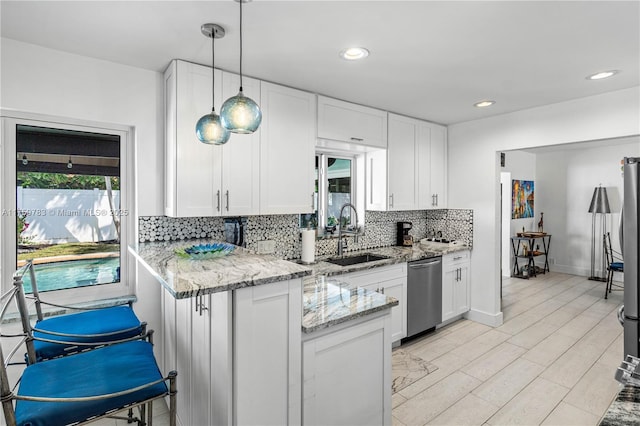 kitchen featuring backsplash, a peninsula, white cabinets, stainless steel appliances, and a sink