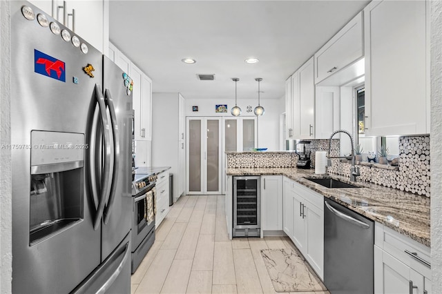 kitchen with a sink, appliances with stainless steel finishes, beverage cooler, and white cabinets