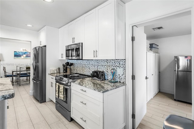 kitchen with light stone counters, decorative backsplash, appliances with stainless steel finishes, and white cabinetry