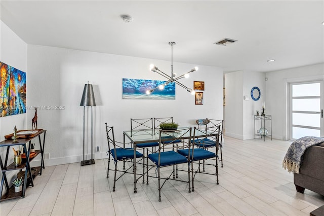 dining area with a notable chandelier, visible vents, light wood-type flooring, and baseboards