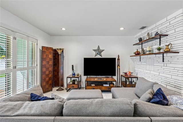 living room with recessed lighting, visible vents, and brick wall