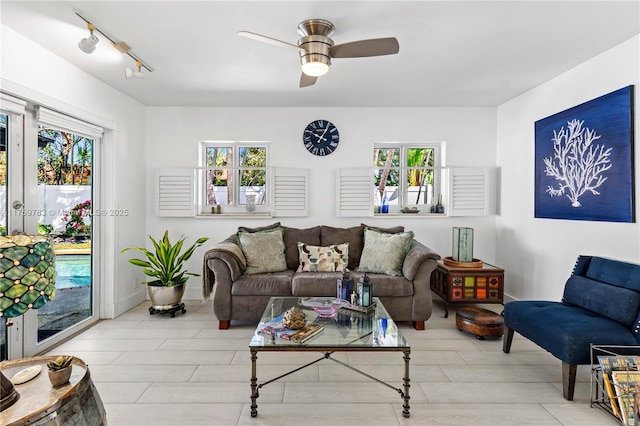 living area with baseboards, a ceiling fan, and rail lighting