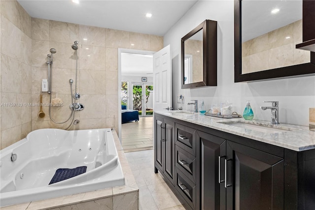 bathroom with double vanity, a jetted tub, tile walls, and a sink