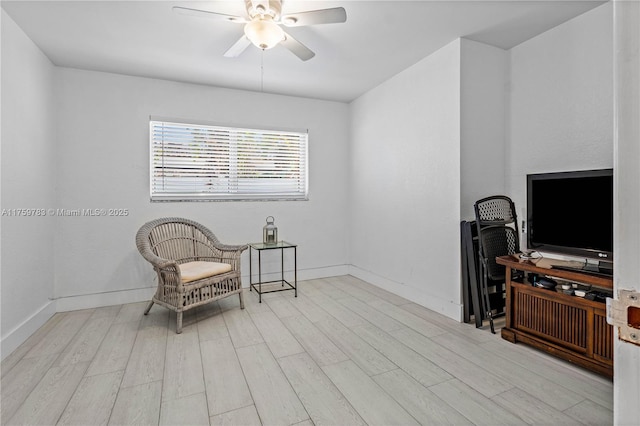 sitting room featuring baseboards, wood finished floors, and a ceiling fan