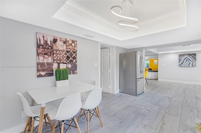 dining room with wood finished floors, baseboards, visible vents, a tray ceiling, and ornamental molding