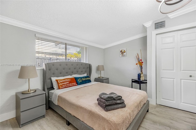 bedroom with visible vents, crown molding, a textured ceiling, and light wood-type flooring