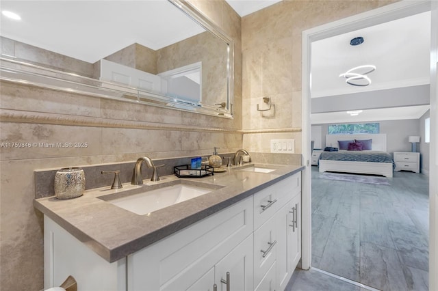 ensuite bathroom with double vanity, connected bathroom, backsplash, and a sink