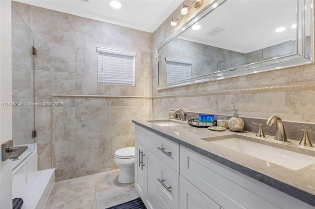 bathroom featuring tile walls, tiled shower, and a sink