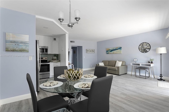 dining room featuring a chandelier, visible vents, baseboards, and light wood-style floors