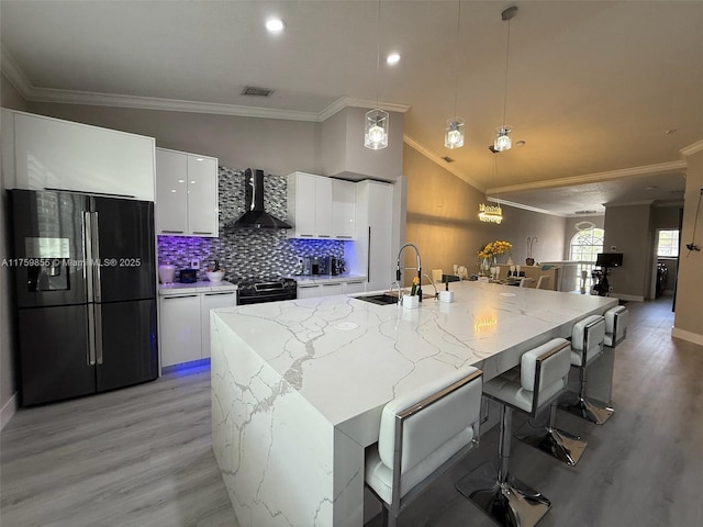 kitchen with visible vents, black fridge with ice dispenser, white cabinetry, a sink, and wall chimney exhaust hood