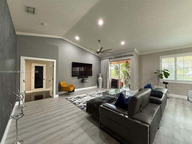 living room with lofted ceiling, visible vents, ornamental molding, wood finished floors, and baseboards