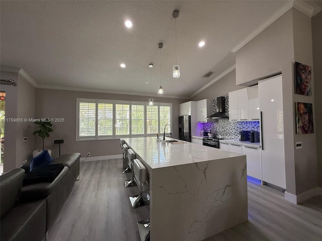 kitchen with ornamental molding, white cabinetry, wall chimney range hood, modern cabinets, and stainless steel range with electric stovetop