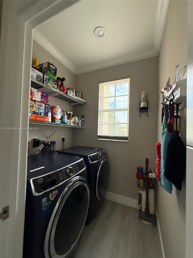 laundry area featuring wood finished floors, laundry area, ornamental molding, and washing machine and clothes dryer