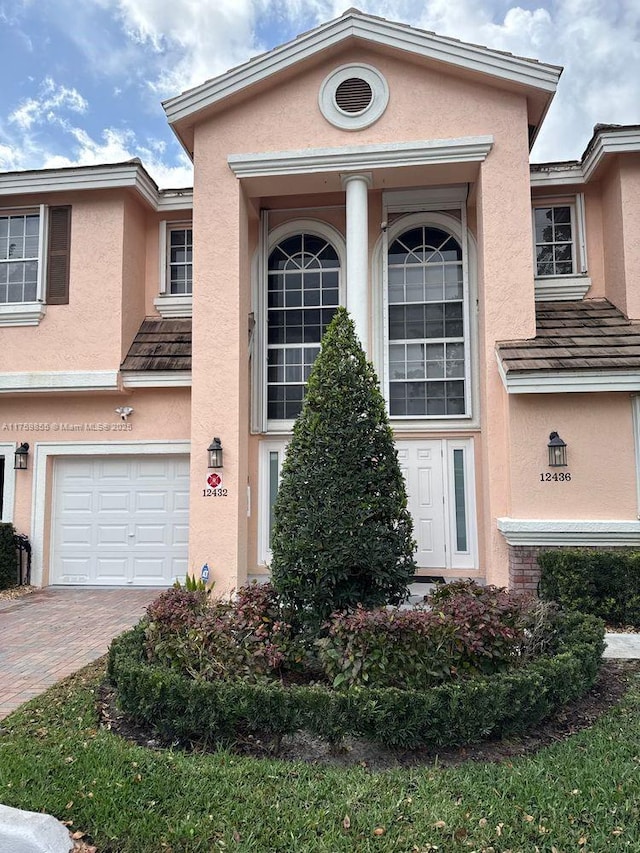 property entrance featuring a garage, decorative driveway, and stucco siding