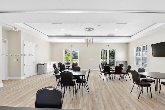 dining space with a paneled ceiling, light wood-style flooring, and baseboards