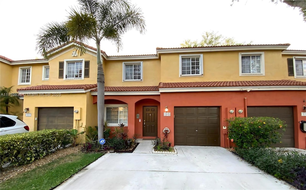 view of front of house with driveway, a tiled roof, an attached garage, and stucco siding