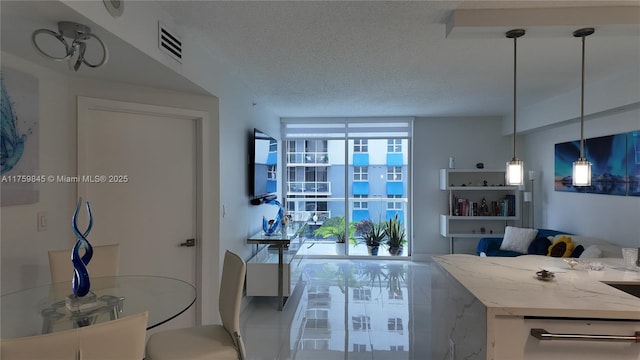 interior space featuring visible vents, floor to ceiling windows, light stone counters, hanging light fixtures, and a textured ceiling