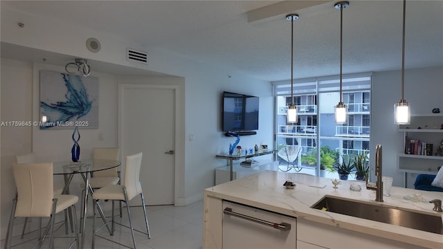 kitchen featuring visible vents, a sink, a textured ceiling, white cabinetry, and light stone countertops