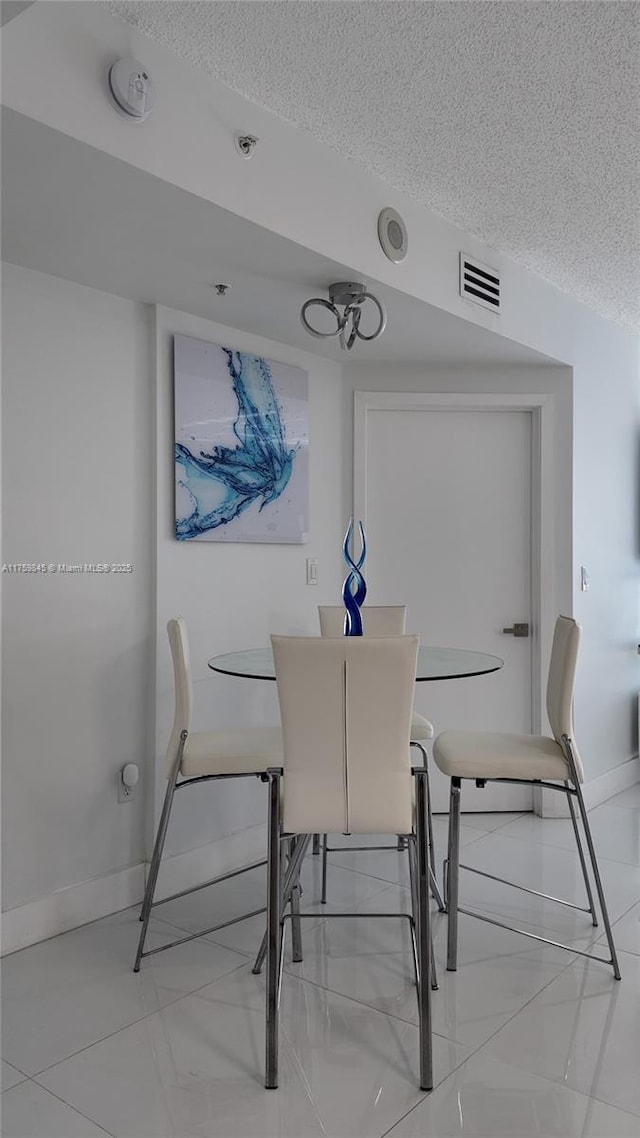 dining area featuring visible vents, baseboards, and a textured ceiling