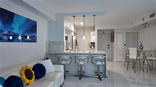 interior space featuring visible vents, light countertops, a peninsula, a kitchen breakfast bar, and refrigerator