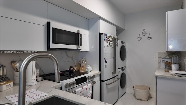 kitchen featuring backsplash, stacked washer / dryer, range with electric cooktop, and refrigerator