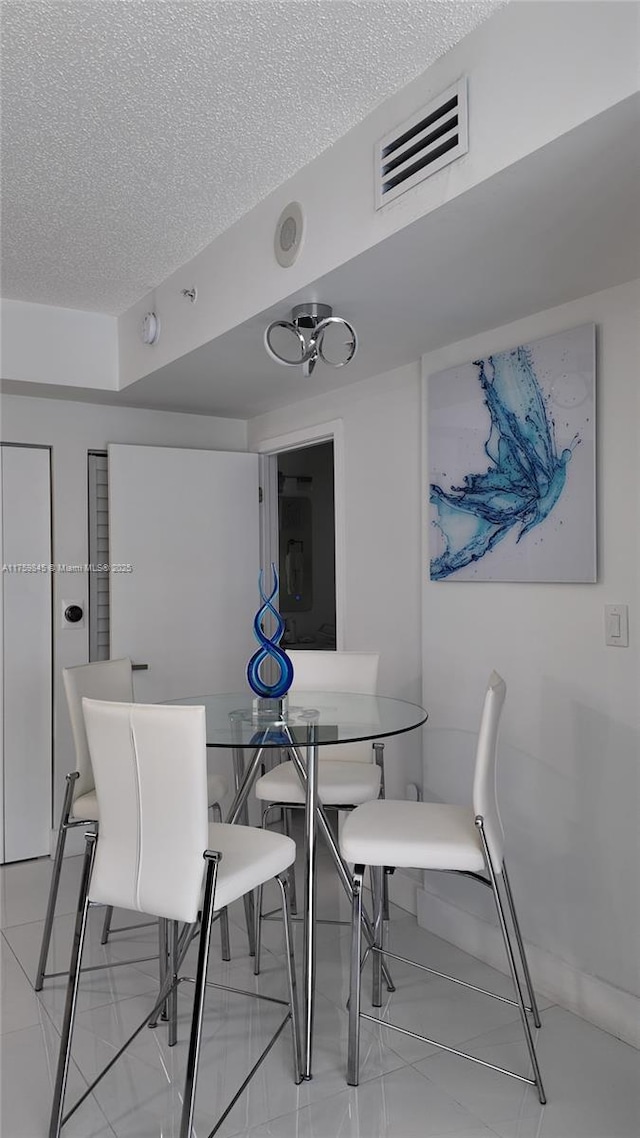 dining space with visible vents and a textured ceiling