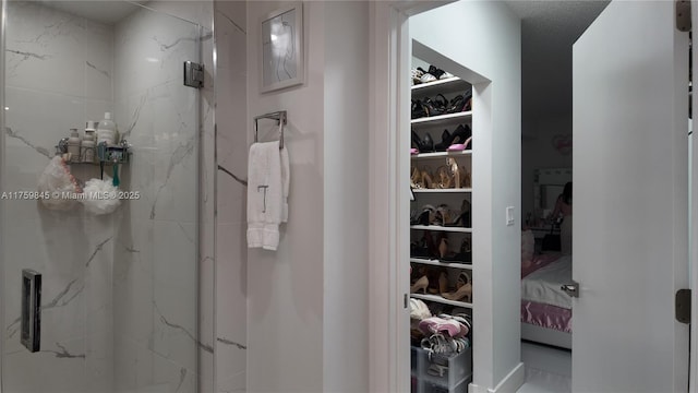 bathroom with a marble finish shower and a spacious closet