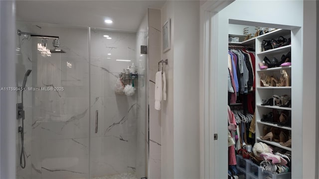 bathroom featuring a spacious closet, recessed lighting, and a marble finish shower