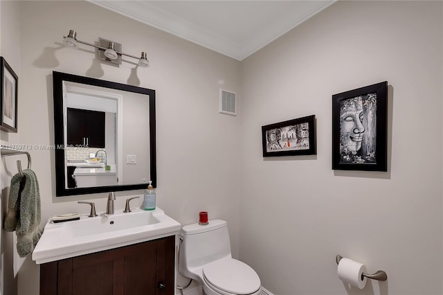 bathroom featuring toilet, ornamental molding, vanity, and visible vents